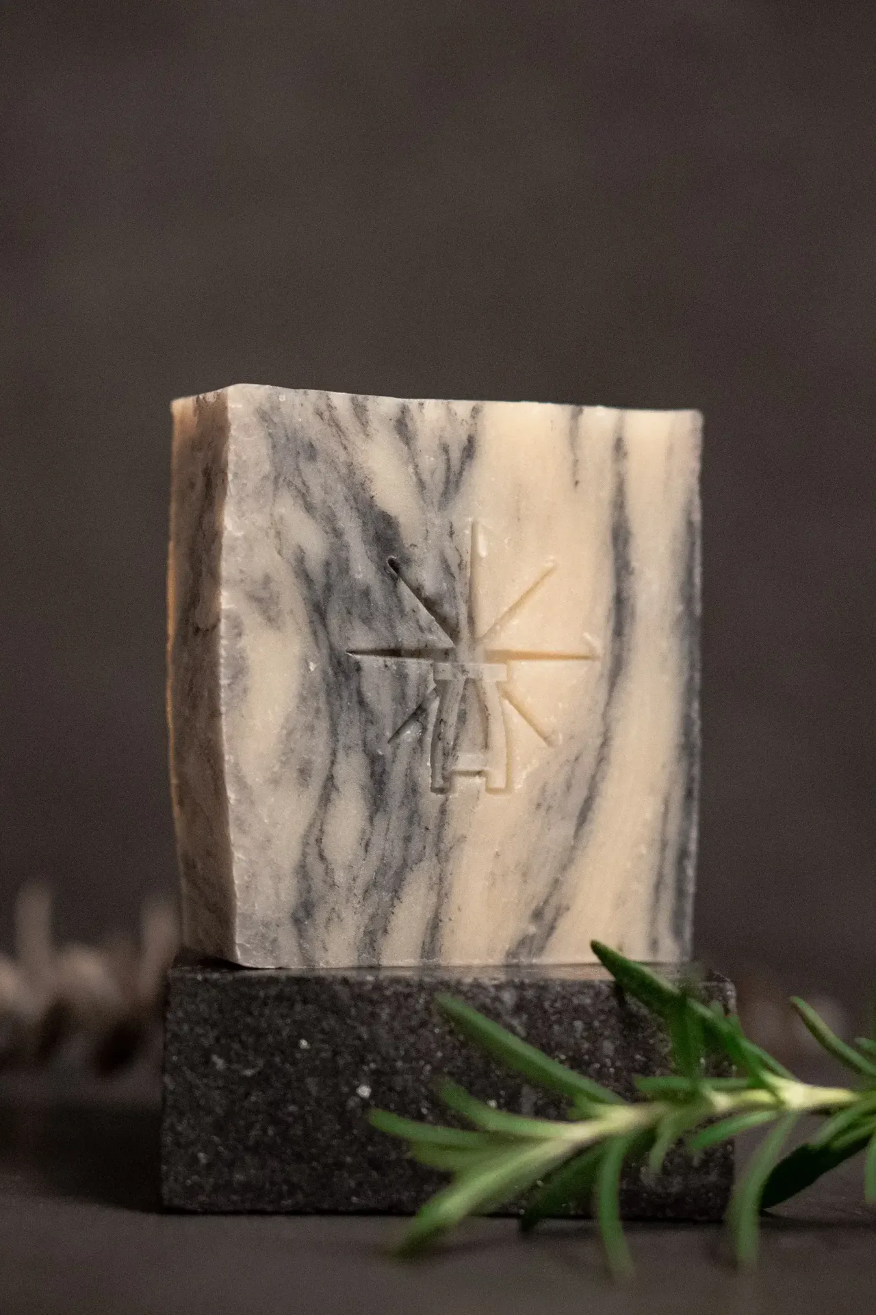 Black Altar Sacred Marble soap—cream and charcoal-swirled bar on dark stone, styled with fresh rosemary, cloves, and a cinnamon stick.