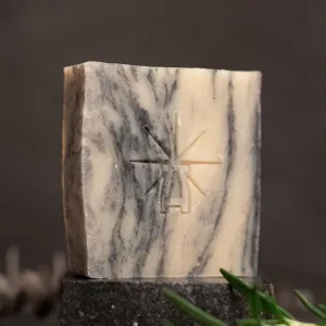 Black Altar Sacred Marble soap—cream and charcoal-swirled bar on dark stone, styled with fresh rosemary, cloves, and a cinnamon stick.