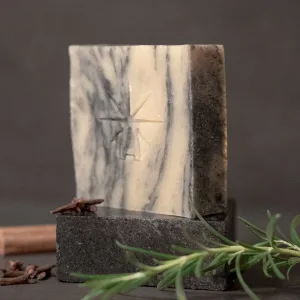 Black Altar Sacred Marble soap—cream and charcoal-swirled bar on dark stone, styled with fresh rosemary, cloves, and a cinnamon stick.