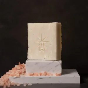 Black Altar Earth Salt soap—creamy off-white bar on stacked white marble blocks, pink Himalayan salt crystals spilling alongside.