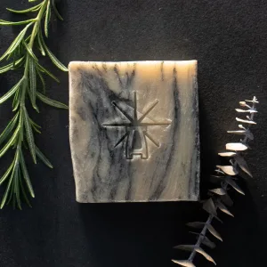 Black Altar Sacred Marble soap on dark backdrop, styled with fresh rosemary and a dried eucalyptus stem.