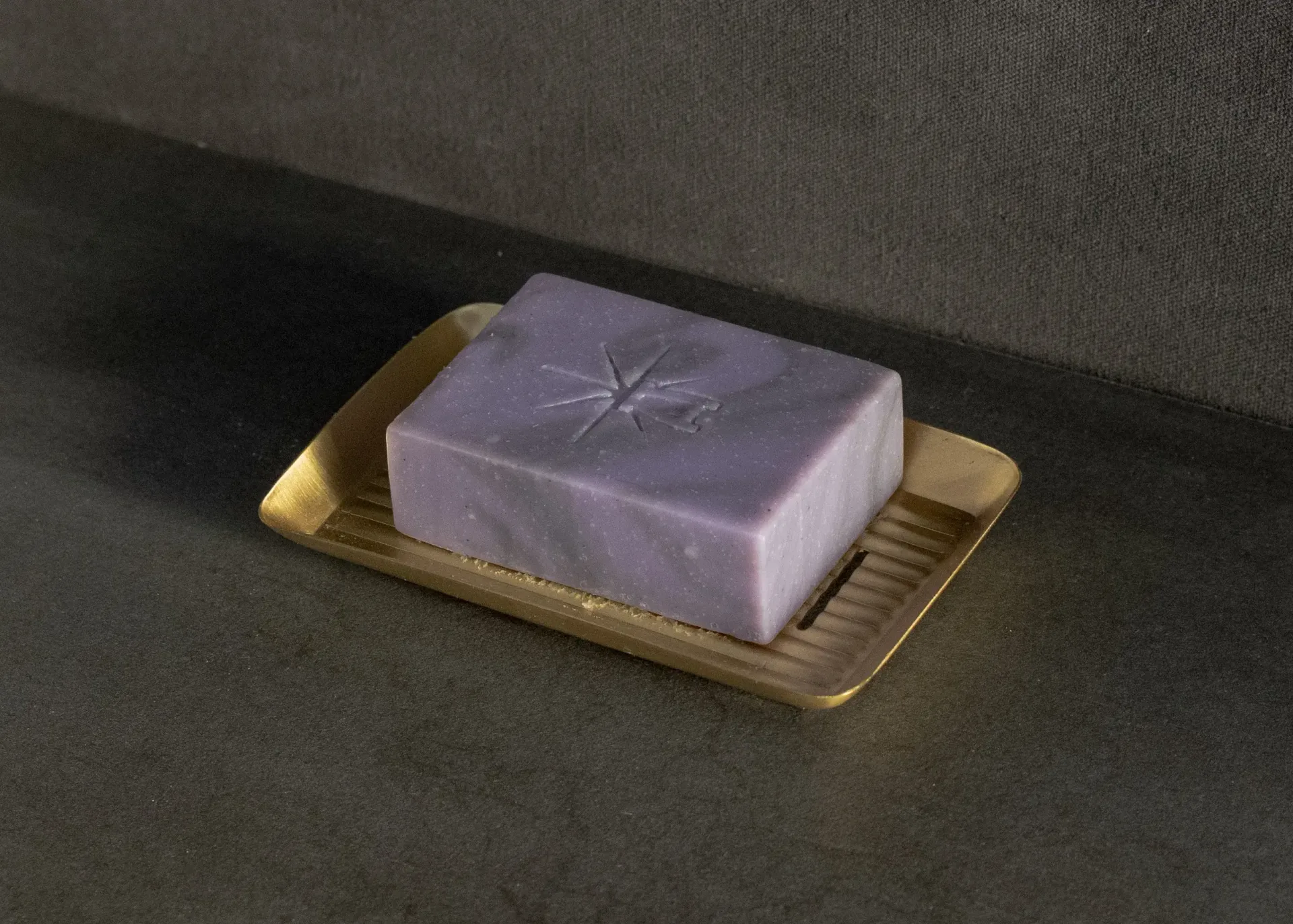 Black Altar Mystic Twilight soap resting in a gold metal dish on a granite countertop.