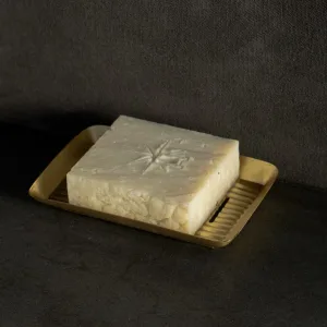 Black Altar Earth Salt soap resting in a gold metal dish on a granite countertop.