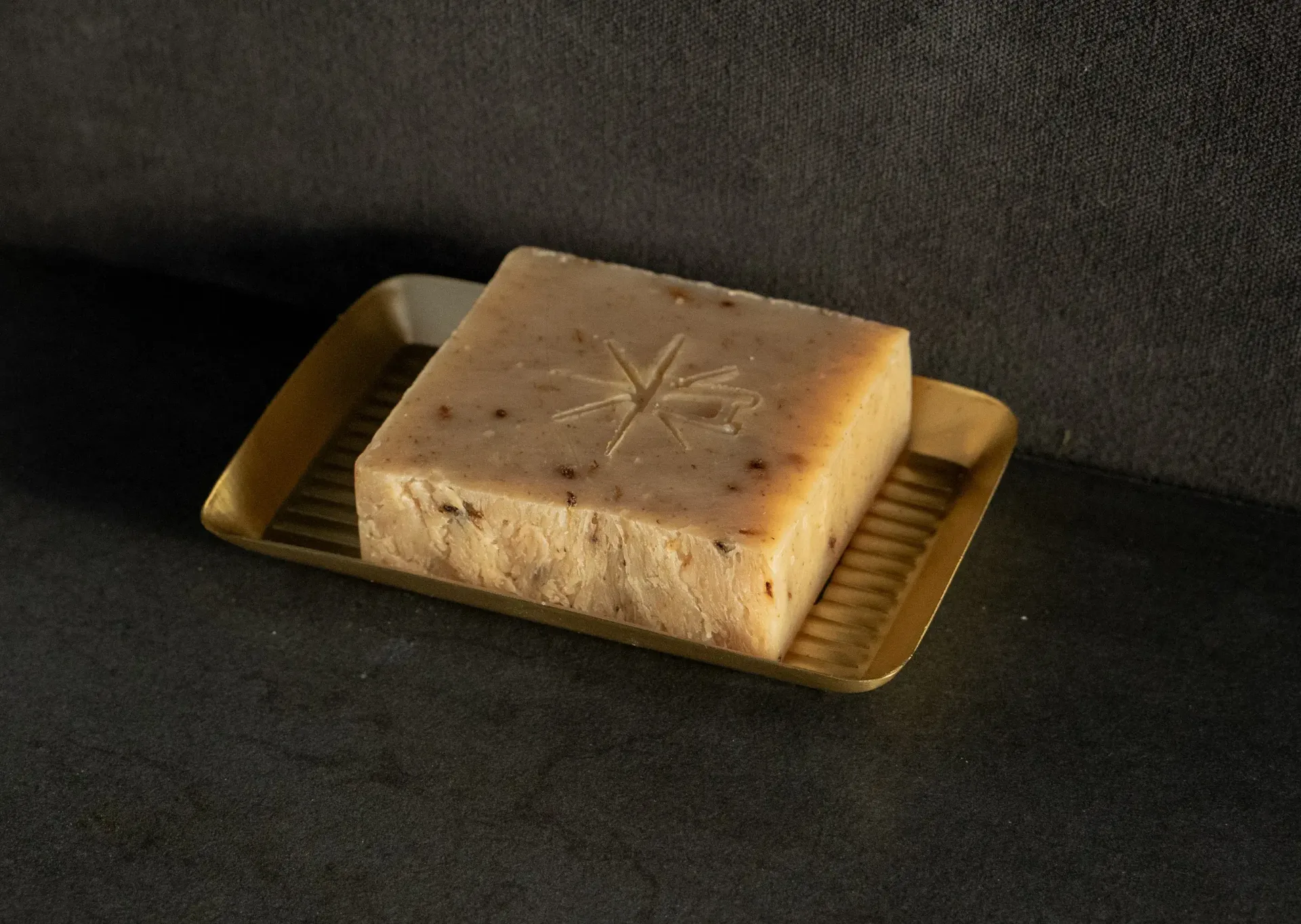 Black Altar Witch Bloom Soap resting in a gold metal dish on a granite countertop.