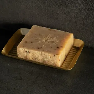 Black Altar Witch Bloom Soap resting in a gold metal dish on a granite countertop.
