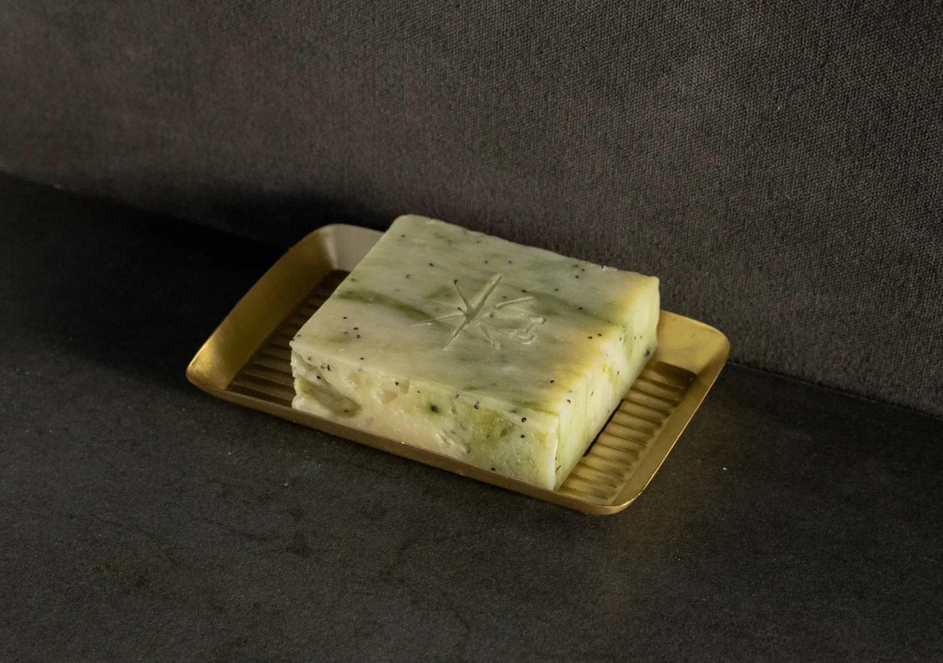 Black Altar Wild Conjuring soap bar resting in a gold metal dish on a granite countertop.