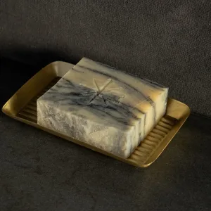 Black Altar Sacred Marble soap resting in a gold metal dish on a granite countertop.