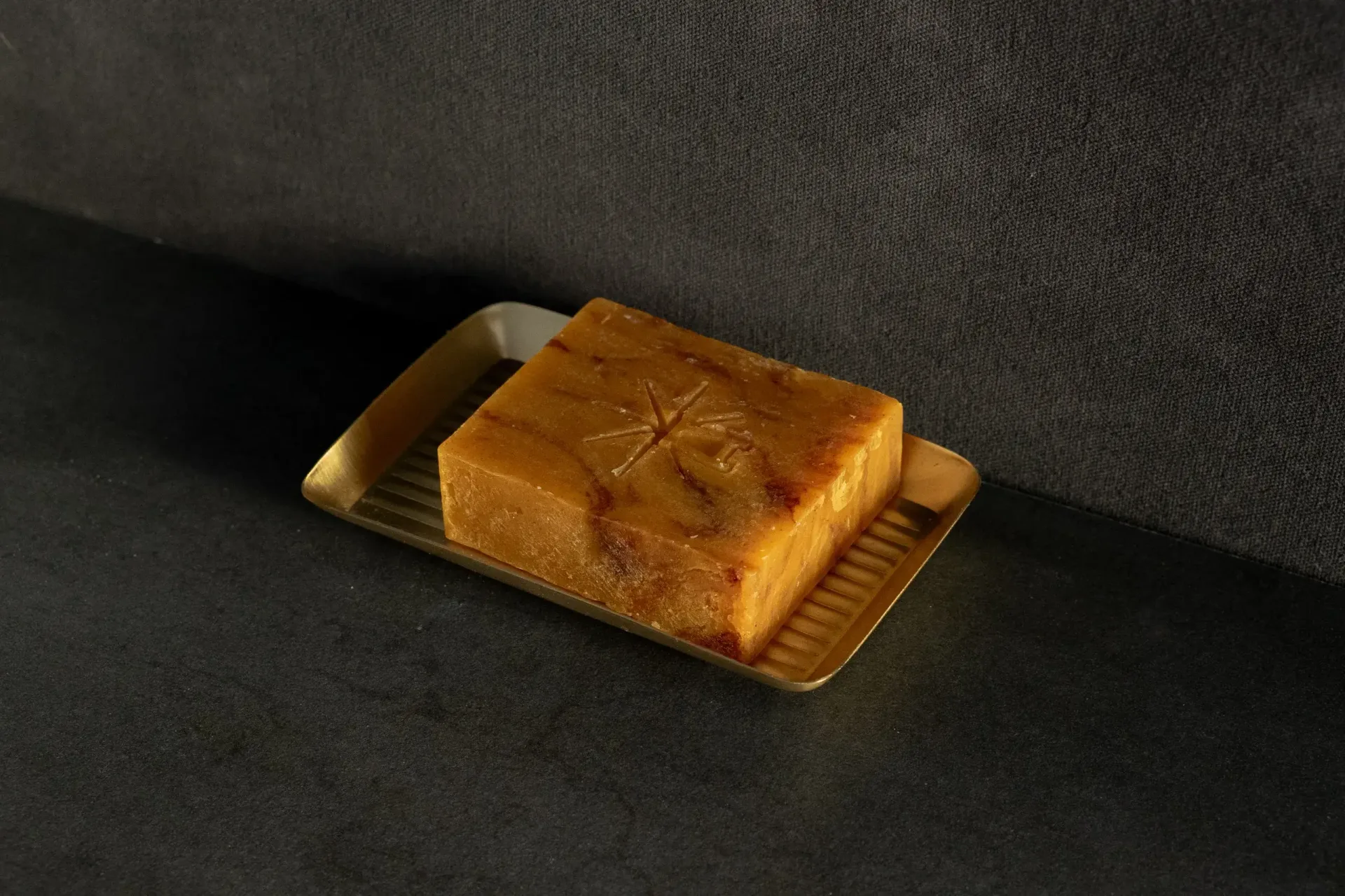 Black Altar Ritual Ember Bar resting in a gold metal dish on a granite countertop.