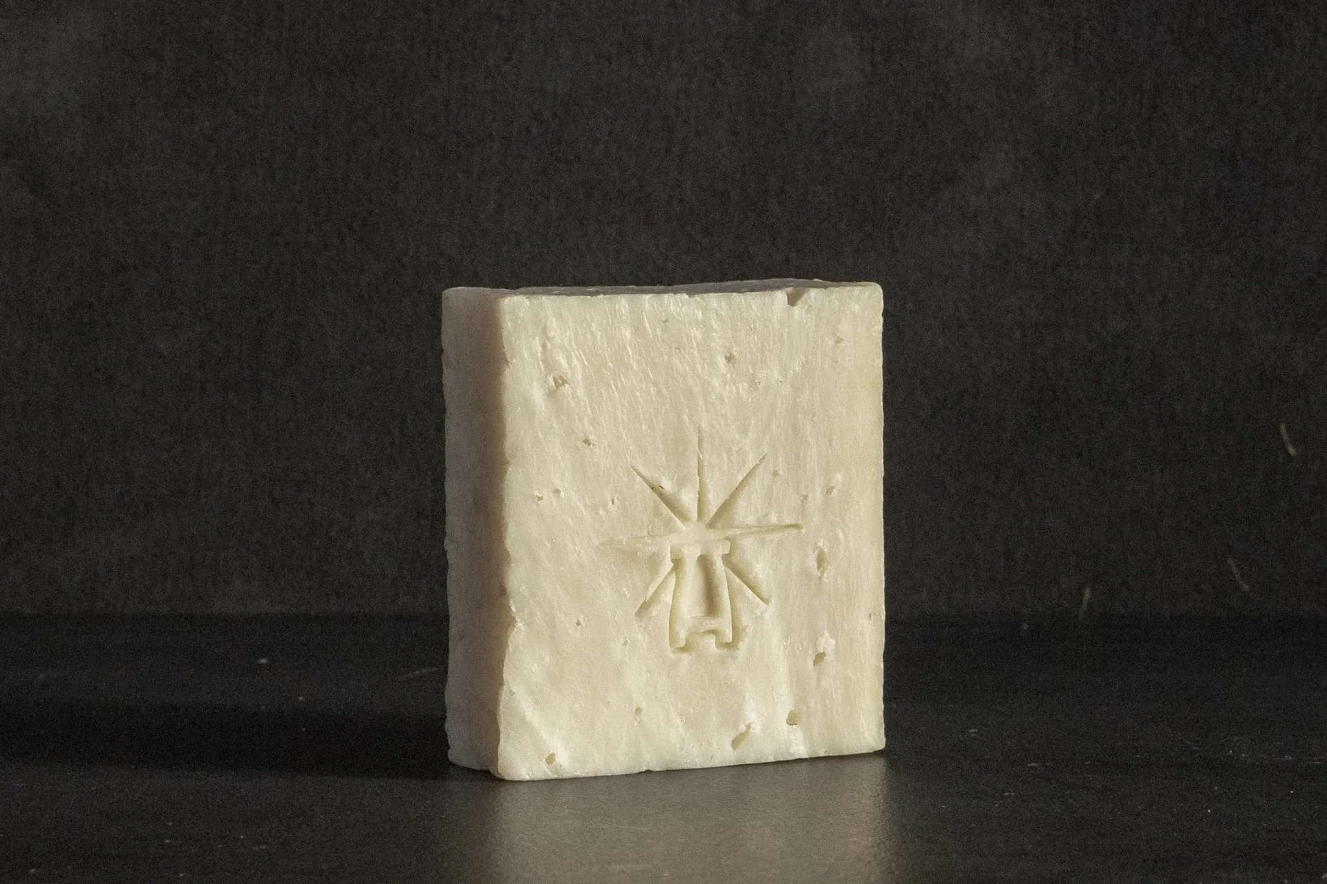 Studio shot of Black Altar Earth Salt soap—creamy off-white bar with subtle salt texture and star-altar logo.