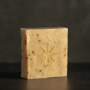 Studio shot of Black Altar Witch Bloom soap—beige botanical bar flecked with herbs, featuring the star-altar logo.