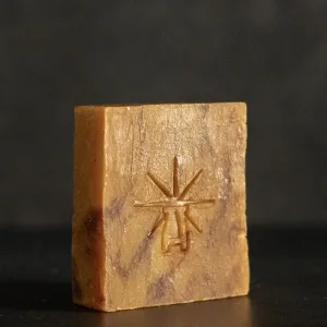 Studio shot of Black Altar Ritual Ember soap—warm amber bar marbled with deeper tones, embossed with star-altar logo.