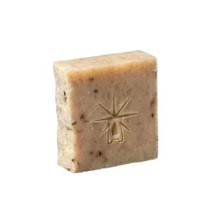 Black Altar Witch Bloom Bar — warm beige botanical soap dotted with herb fragments, star-altar logo stamped. lavender-sage soothing exfoliating bar