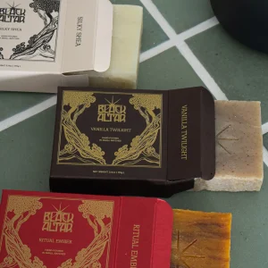 Black Altar boxed soaps and loose amber bar arranged around a black candle