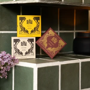 Black Altar boxed soap trio in yellow, cream, and mauve packaging on green tile