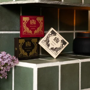 Stacked Black Altar soap boxes in red, cream, and black gold packaging