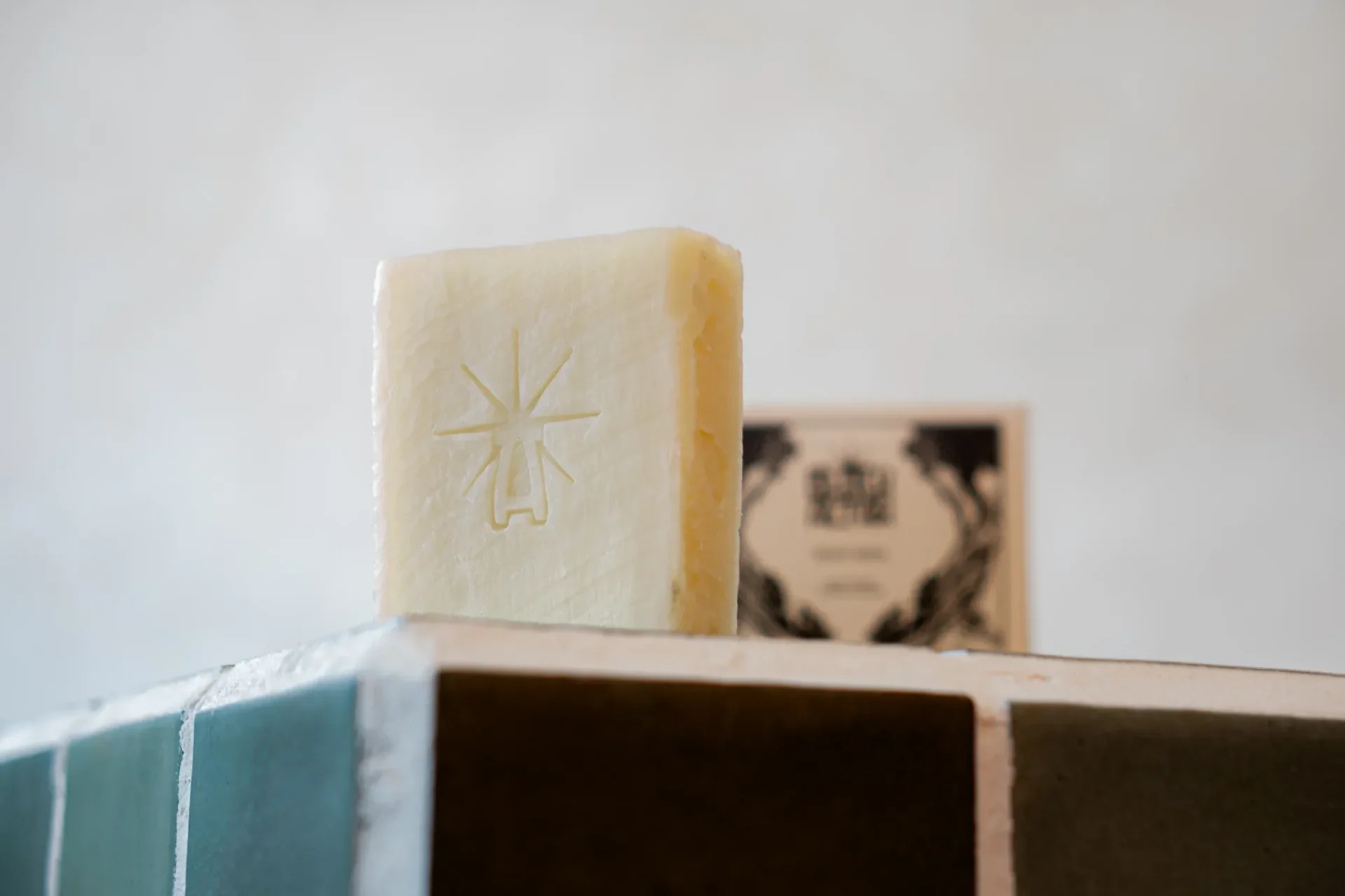 Single pale cream Black Altar stamped soap bar standing on a tiled ledge