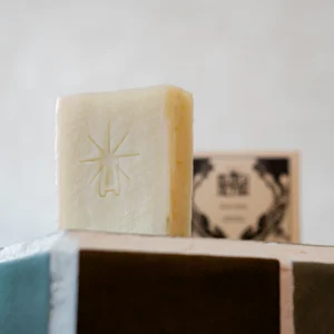 Single pale cream Black Altar stamped soap bar standing on a tiled ledge