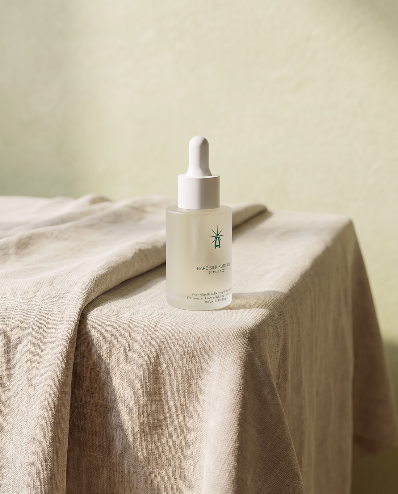 Bare Silk body oil bottle on a linen-draped table